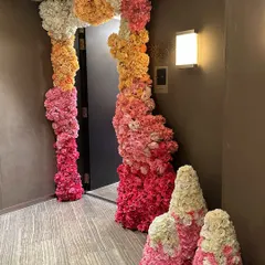 This home wedding decor features a stunning floral installation that flows from a console table and frames a doorway, using a beautiful ombre effect with pink, orange, and white flowers.
