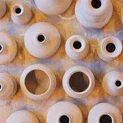 A top-down view of various unfired pots, fresh off the potter's wheel. Each one has its own subtle personality, showcasing the beauty of handmade variations.