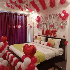 Another view of the red and white romantic room setup, showing balloon pillars with heart foil toppers.