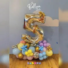 A beautiful and delicate balloon arrangement for a fifth birthday, featuring a large silver number five surrounded by pastel balloons and whimsical butterfly accents.