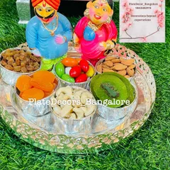 This dry fruit platter features hand-painted Marapachi Bommai dolls, adding a vibrant and personal touch to the wedding seer varisai.