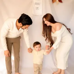 A precious milestone: baby's first steps. With his parents holding his hands for support, this photo from a first birthday session is a beautiful memory of growth and family encouragement.