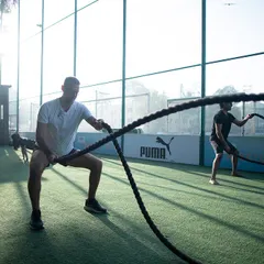 Two members using battle ropes with intense focus. This shows that our workouts incorporate modern functional tools alongside traditional ones for a comprehensive, high-intensity session.
