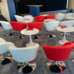 Modern and stylish seating for a corporate event or conference, featuring red and white bucket chairs with sleek tulip side tables.