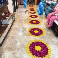 A walkway decorated with circular flower rangolis and balloon pillars to welcome a new baby home.