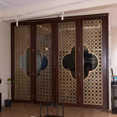 This set of four folding doors features intricate CNC-cut 'jali' work with a gold matte finish over a rich brown PU painted HDHMR base. It's a perfect solution for dividing a room while maintaining a sense of openness and artistry.