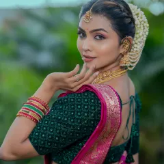 This side-back view shows how the hairstyle, makeup, and blouse design all work together. The soft braid is adorned with jasmine, complementing the traditional South Indian bridal look.