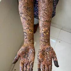Another view of Arfa's bridal henna, highlighting the intricate floral work on the palms and the detailed checkerboard patterns on the fingers.