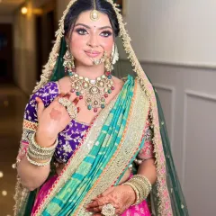 A candid shot showing the intricate details of the jewelry and the flawless makeup. The fresh flower in her hair adds a lovely touch.