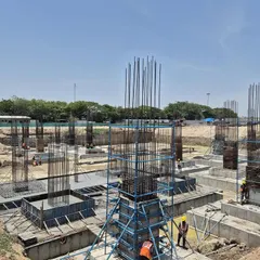 Construction progressing at the TIDEL Park site, with concrete columns and rebar cages rising from the foundation. This phase establishes the structural grid for the 600,000 sq. ft. campus.