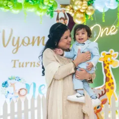 A sweet moment between mother and son at his first birthday. The jungle-themed decor adds a fun and colorful backdrop to this heartwarming candid photograph.