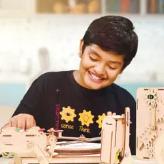 The smile of a maker! This student is proudly working with one of our custom-designed wooden robot kits. We create these kits to be engaging and accessible, allowing kids to understand mechanical and electronic principles through hands-on assembly.