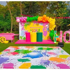 A colourful and fun setup for a Holi party. The backdrop is a splash of bright colours, with large 'HOLI' letters and a custom dance floor designed to look like it's covered in paint.
