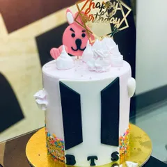 A 1.5kg BTS-themed cake with the iconic logo, sprinkles, and a cute character topper.
