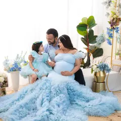 A portrait of a family on the cusp of a new beginning. The flowing blue gowns and soft floral background create a dreamy, serene atmosphere for this maternity session.