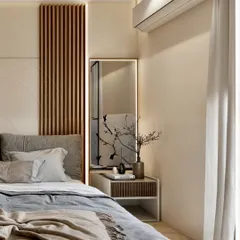 This bedroom corner shows how to create a cozy sanctuary using warm neutral colors and soft lighting. The vertical wood paneling behind the bed adds texture and visual interest, complemented by a simple, elegant bedside table and a backlit mirror. It's a perfect example of how to use layered textures to make a space feel inviting.