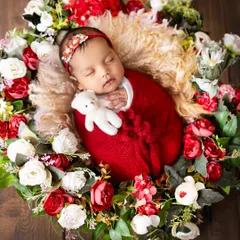 This sweet newborn is cuddled up with a tiny teddy bear, nestled in a bed of red and white flowers. Adding a small prop like a toy can add a touch of sweetness to the portrait.