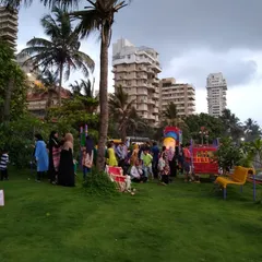 A wide view of the park on its opening day, filled with local residents. The design focused on providing an open, green lawn area for unstructured play and community gathering, set against the backdrop of the sea.