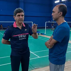A close-up of Prakash Padukone mentoring a senior coach on the court. This direct access to his strategic mind is a unique and invaluable part of the learning experience I provide.