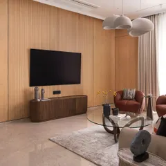 Soft tones and sculptural forms create effortless warmth in this living room. I brought together fluted wood panels, cozy textures, and organic curves to design a space that feels calm, modern, and deeply lived-in.