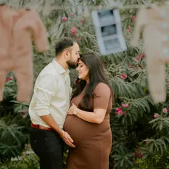 A tender kiss shared behind the sweet announcement of their coming baby. This photo combines romance with the excitement of a pregnancy announcement.