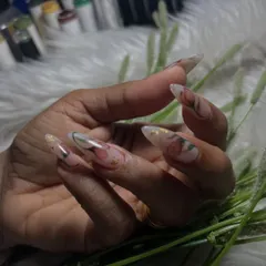 A delicate and dreamy floral design on long almond-shaped extensions. The soft, translucent flowers are accented with tiny gold flakes, creating a look of blooming beauty that is perfect for any special occasion.