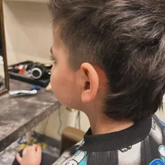 The side view of this kid's mullet shows the clean fade on the sides, which contrasts with the textured length on top and in the back.