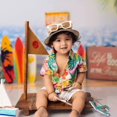 Ready for an adventure! This little explorer is all set for his beach-themed photoshoot, complete with a hat, sunglasses, and a toy boat.