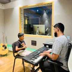 A vocal student works with his instructor at the keyboard. This shows our integrated approach to teaching, where students learn melody and harmony alongside their primary instrument.