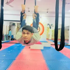 A young student enjoying the fun of aerial yoga. This inverted pose is not only playful but also helps to build body awareness and strength in a safe, supported way.