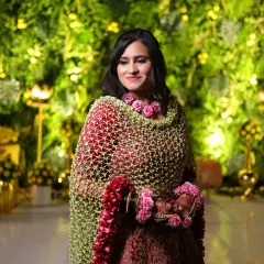 A full view of the bride wearing the red rose border floral shela. It drapes beautifully over her red lehenga, creating a look of pure opulence.