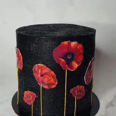 A still shot of the stunning poppy cake. The vibrant red of the edible wafer paper poppies stands out beautifully against the shimmering black buttercream.