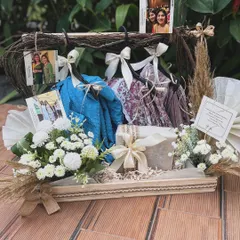 A wider view of the hanger hamper, showcasing the full arrangement on a rustic tray. The combination of natural textures, soft florals, and personal mementos makes this a heartfelt and creative gift.
