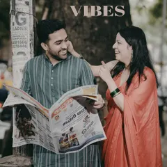 A retro-themed pre-wedding photo where the couple shares a laugh while reading a newspaper, creating a candid and nostalgic scene on a Bangalore street.