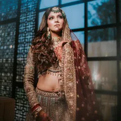 A moody and artistic shot of the bride. The makeup, with its defined eyes and contoured features, looks striking against the dramatic lighting.