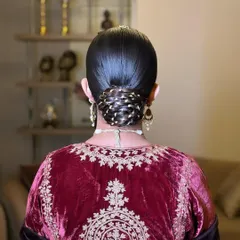 This is a 'Gotta Bun', where a traditional gotta patti lace is woven into a sleek, twisted bun. It’s a beautiful way to incorporate elements of your outfit into the hairstyle for a cohesive look.