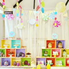 This Candyland-themed dessert and candy bar was the highlight of a fun, celebratory event. I used brightly painted wooden crates to build a dynamic display for a variety of sweets, with hanging candy decorations and a soft curtain backdrop to complete the playful look.