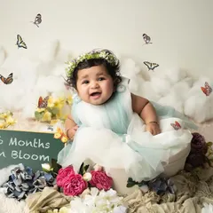 "Six Months in Bloom." This photo celebrates the half-year milestone with a beautiful floral and butterfly theme, capturing her joyful and curious spirit.
