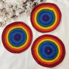 A set of three handmade rainbow doilies. These are perfect for adding a pop of color to a side table or for use as cheerful coasters.