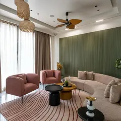 A cozy living space where a curved beige sofa is set against an olive green fluted wall. The design combines soft, sculptural furniture with natural textures and earthy tones for a warm, minimalist aesthetic.