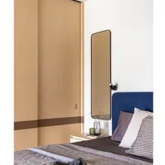 Another view of the bedroom, showing the minimalist bedside table and the sleek, modern mirror. The space is uncluttered and calming.