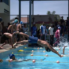 This action shot captures the perfect aerodynamic form of a racing dive, minimizing splash and maximizing forward momentum from the very start.