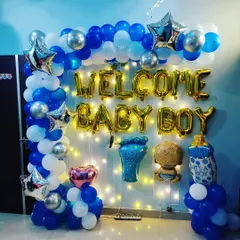 A beautiful wall decoration to welcome a baby boy. The setup is built around a frame with fairy lights and features a blue, white, and silver balloon frame, 'Welcome Baby Boy' foil letters, and cute baby-themed balloons.