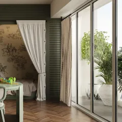 A view from the play area towards the balcony, showing how the room is filled with natural light. The herringbone wood flooring and sage green furniture create a stylish yet child-friendly space.