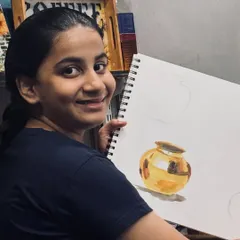 Nothing makes us happier than seeing a student proud of their progress. Here, a student from our elementary batch shows off her beautifully rendered metal pot, mastering light and shadow.