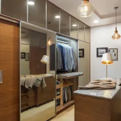 The walk-in closet at Ridge View is designed for ultimate organization. Tall, mirrored shutters open to a mix of wardrobes and drawers, while a central island offers a dedicated space to arrange outfits. It’s a practical, hyper-personalized storage solution.