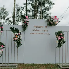 A modern and minimalist welcome backdrop designed for an event at Kikkeri Farm. The clean white wall was accented with asymmetrical floral arrangements, creating a chic and stylish photo opportunity for arriving guests.