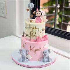 Turning ONE never looked so dreamy! This two-tier cake for a first birthday features adorable fondant elephants, a princess topper, and a soft pink and white color palette.