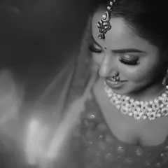 A soft, artistic close-up of the bride. This black and white portrait beautifully highlights her intricate jewelry, makeup, and serene expression on her wedding day.