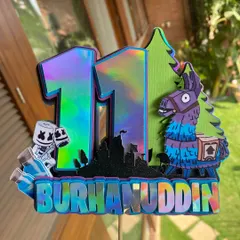 Our Fortnite topper ready to go on a cake. The layered cardstock design is mounted on a clear stick, making it look like it's floating above the celebration.